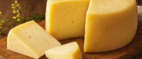 Forma di formaggio semistagionato artigianale della Latteria Donna Tina, presentata su tagliere di rovere.